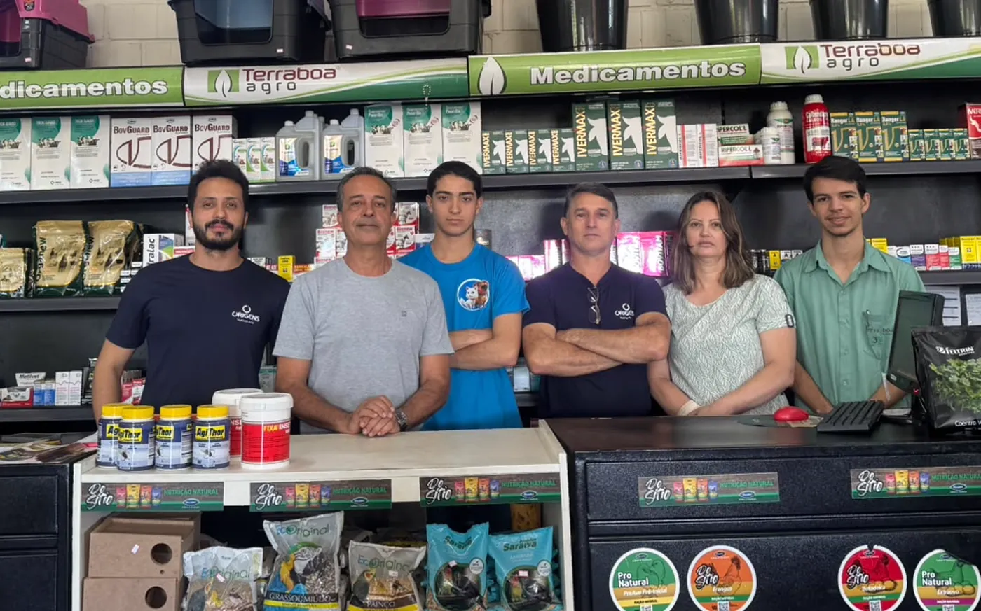 A equipe da Terra Boa atrás do balcão da loja, com a prateleira de medicamentos ao fundo