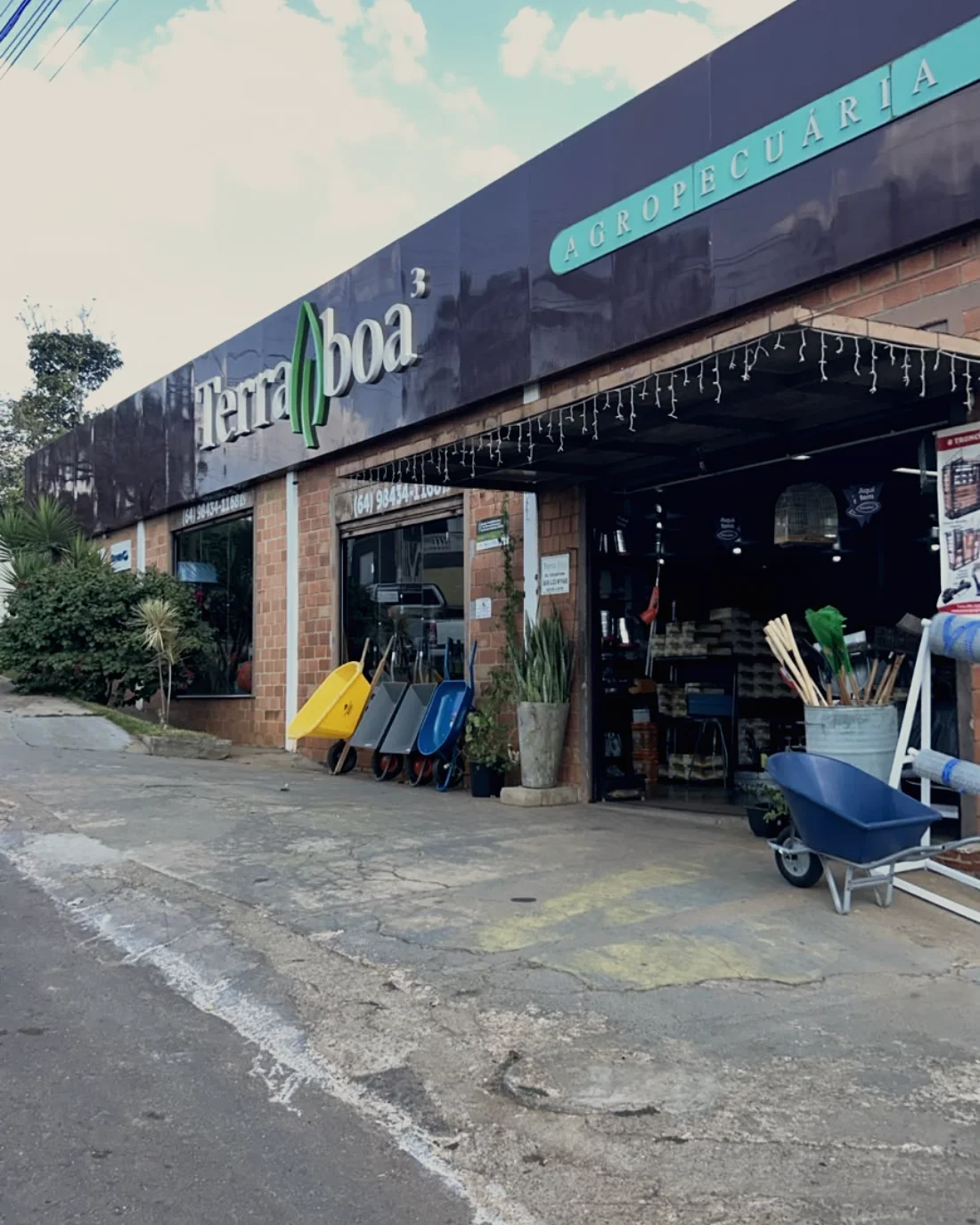 Fachada da Terra Boa em dia de céu azul, com carrinho de mão na calçada